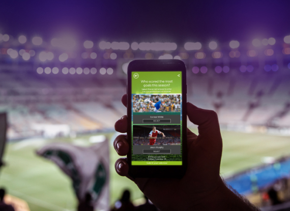 Phone being held up at a football match, showing an Audience Interact vote Phone being held up at a football match, showing an Audience Interact vote